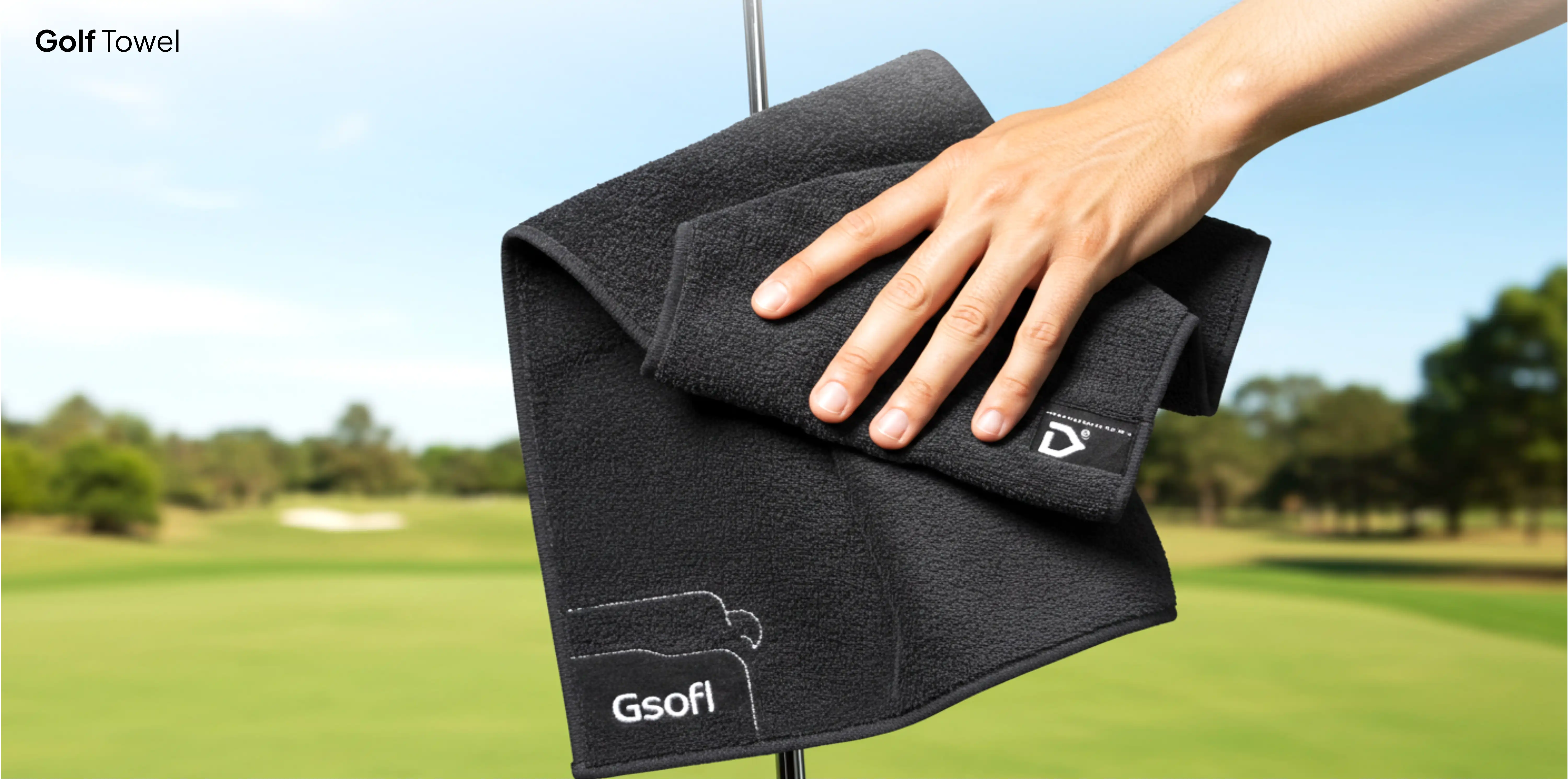 Hand wiping black golf towel.