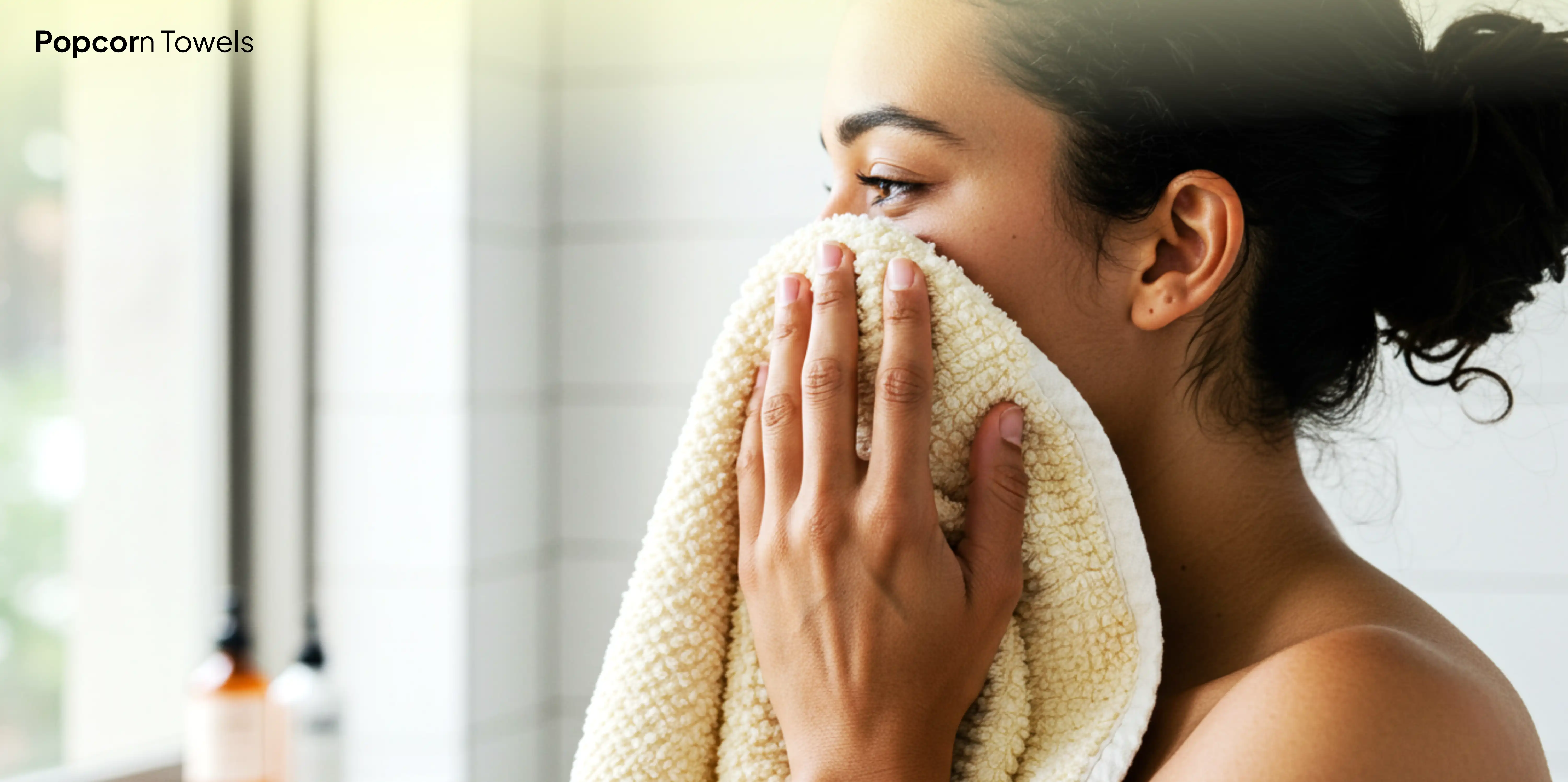 Person holding towel to face in bathroom.